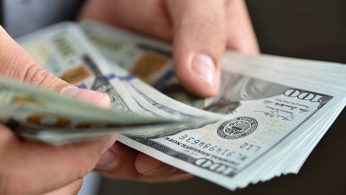 $100 bills in someone's hands.