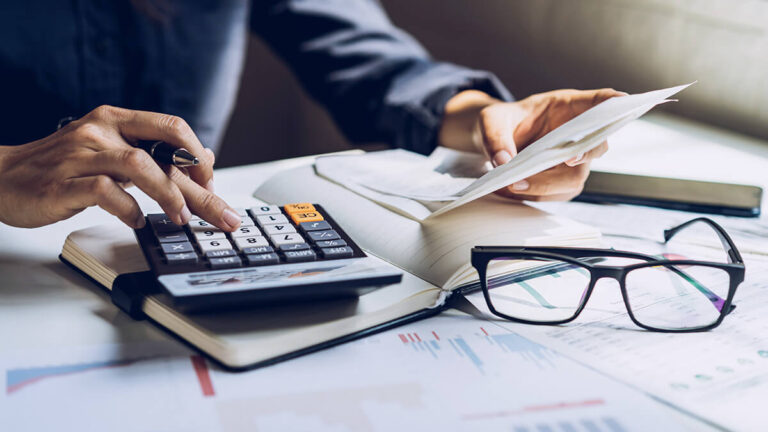 Man doing a trial balance using a calculator.