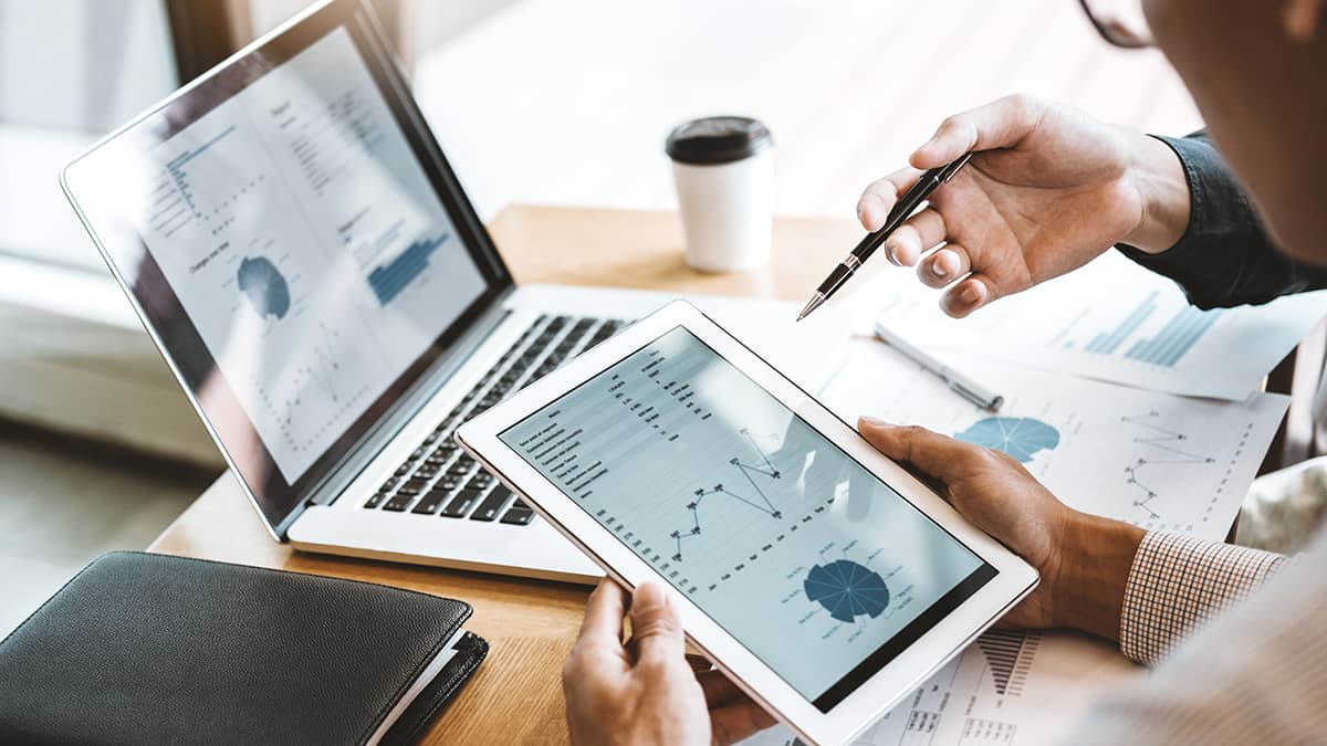 Business budgets and statements on a tablet and laptop.