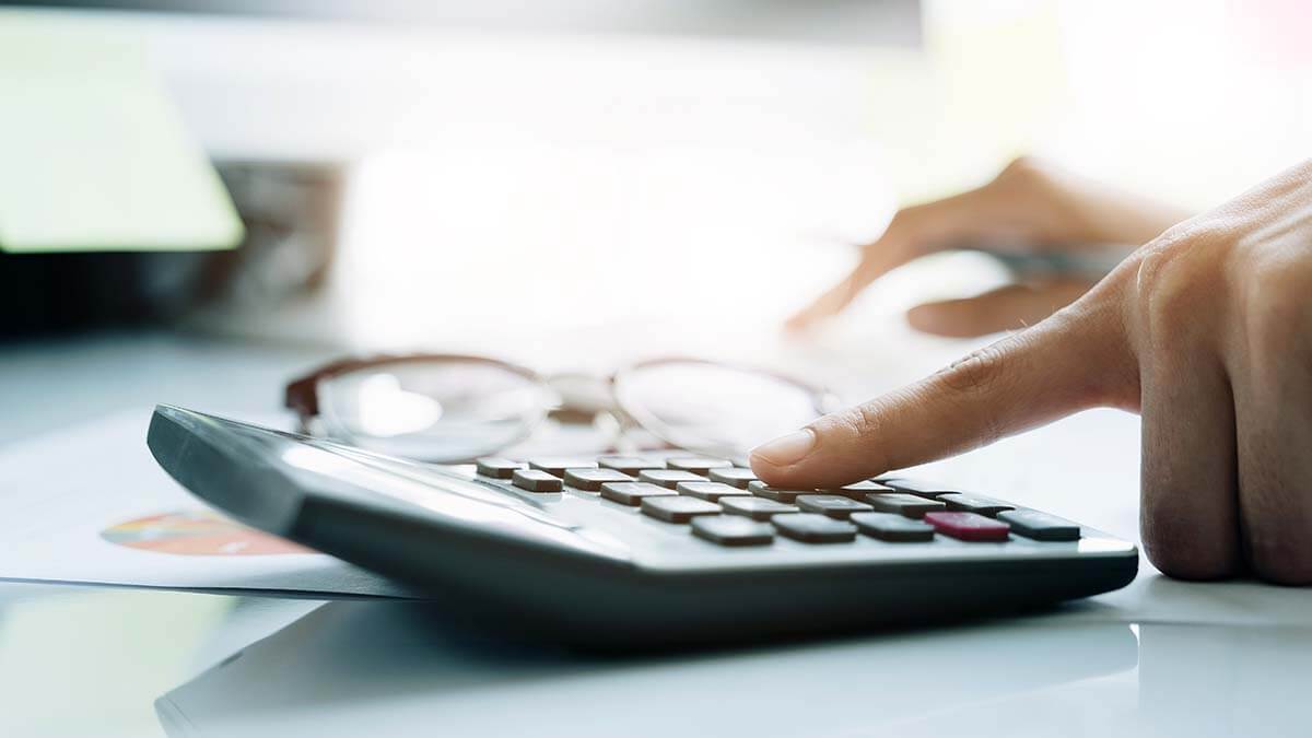 Hands typing on a calculator.