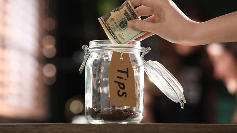 Customer putting $20 in a tip jar.