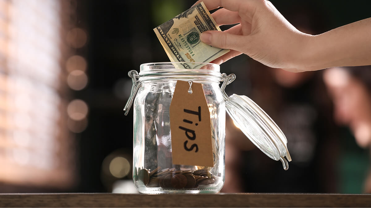 Customer putting $20 in a tip jar.