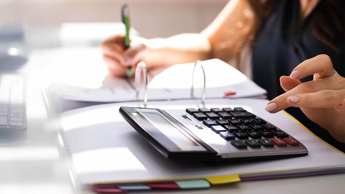Woman using a calculator to calculate gross wages at her desk.