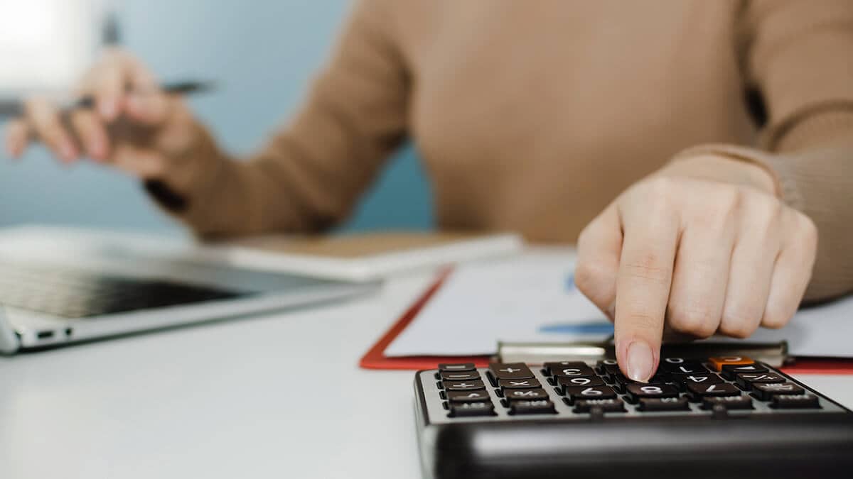 Business owner sitting at a desk, using a calculator.
