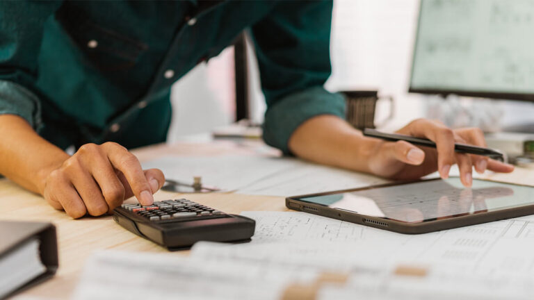 Business owner using a tablet and calculator.