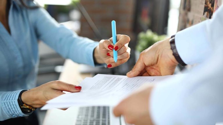 Woman handing a signed contract to a salesperson.