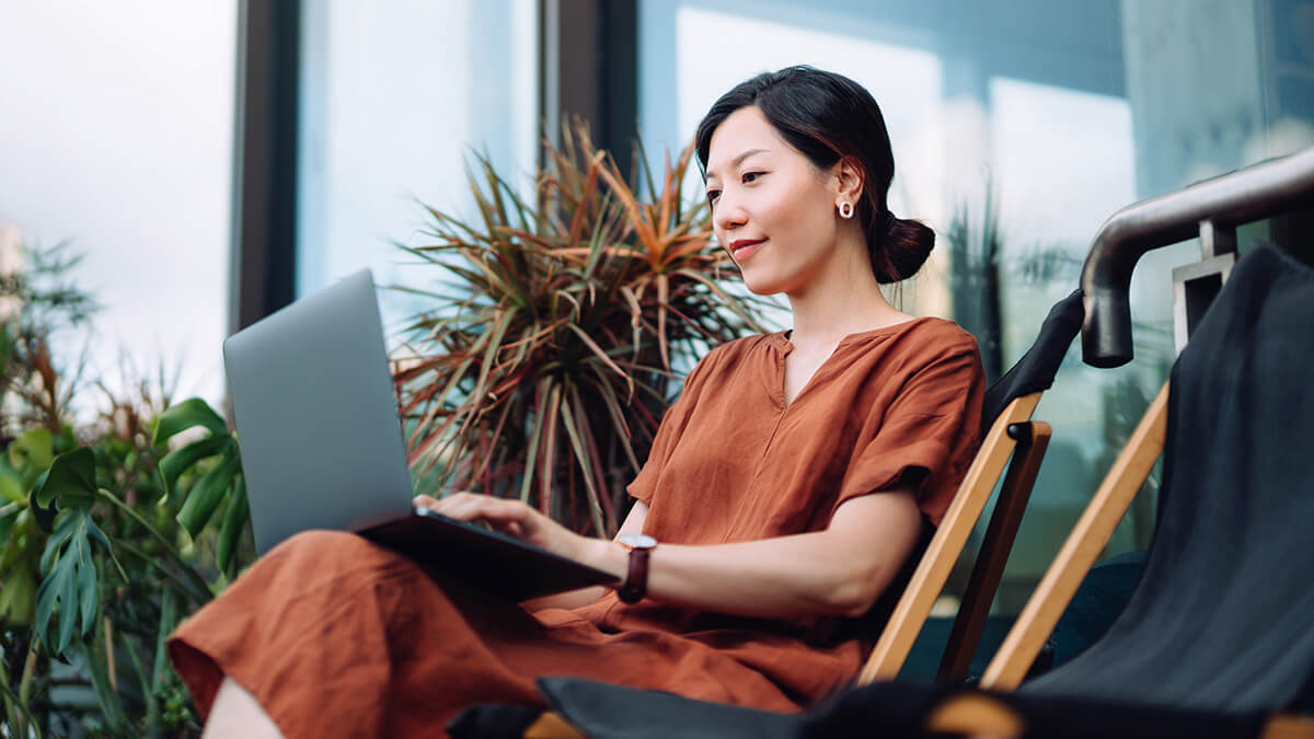 Woman in a burnt orange dress working on laptop.