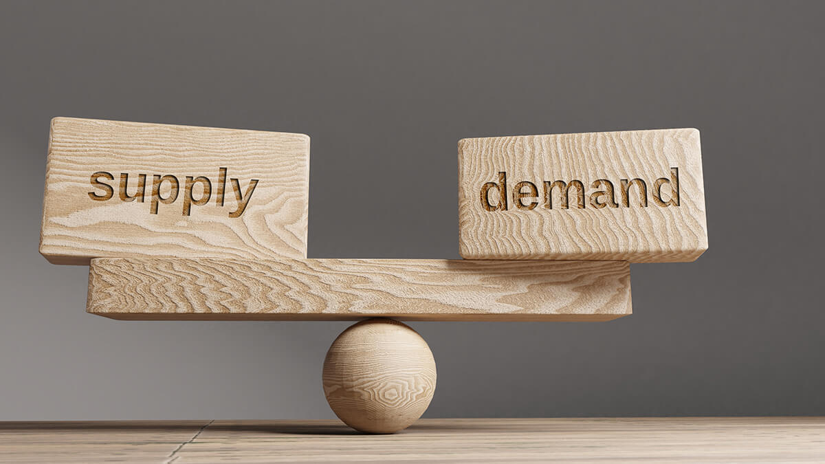 Wooden balance beam with "Supply" and "Demand" blocks on opposite sides.