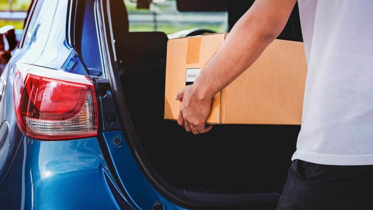 Man putting a moving box in the trunk.