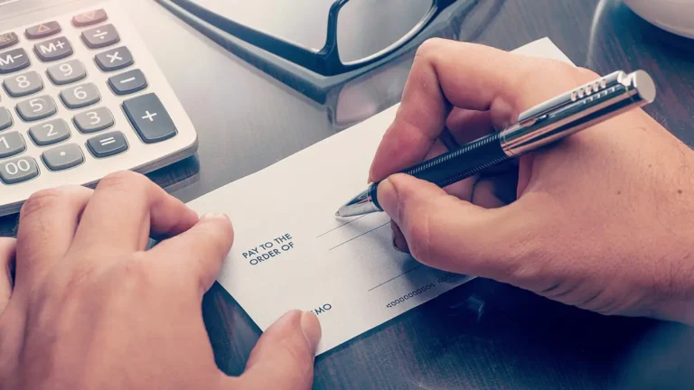 Entrepreneur writing a check to bootstrap his business.