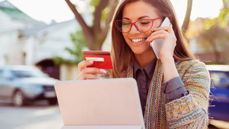 Smiling woman entering her business credit card information into a tablet.